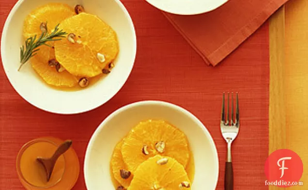 नारंगी-फूल सिरप और कैंडिड हेज़लनट्स के साथ कटा हुआ संतरे