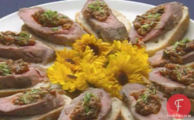 लहसुन-काली मिर्च क्रोस्टिनी पर परोसे गए टमाटर हैश के साथ कटा हुआ भेड़ का बच्चा